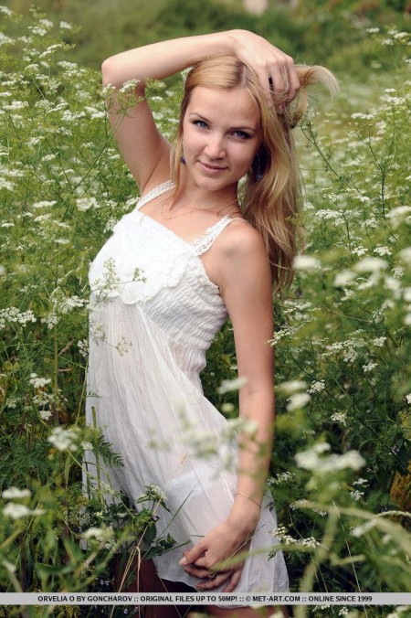 Белокурая нимфа Orvelia O ничего не надела среди цветочных лугов