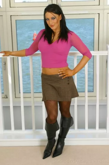 Темноволосая детка Naughty Ness в темных колготках снимает свою розовую блузку и показывает свои 